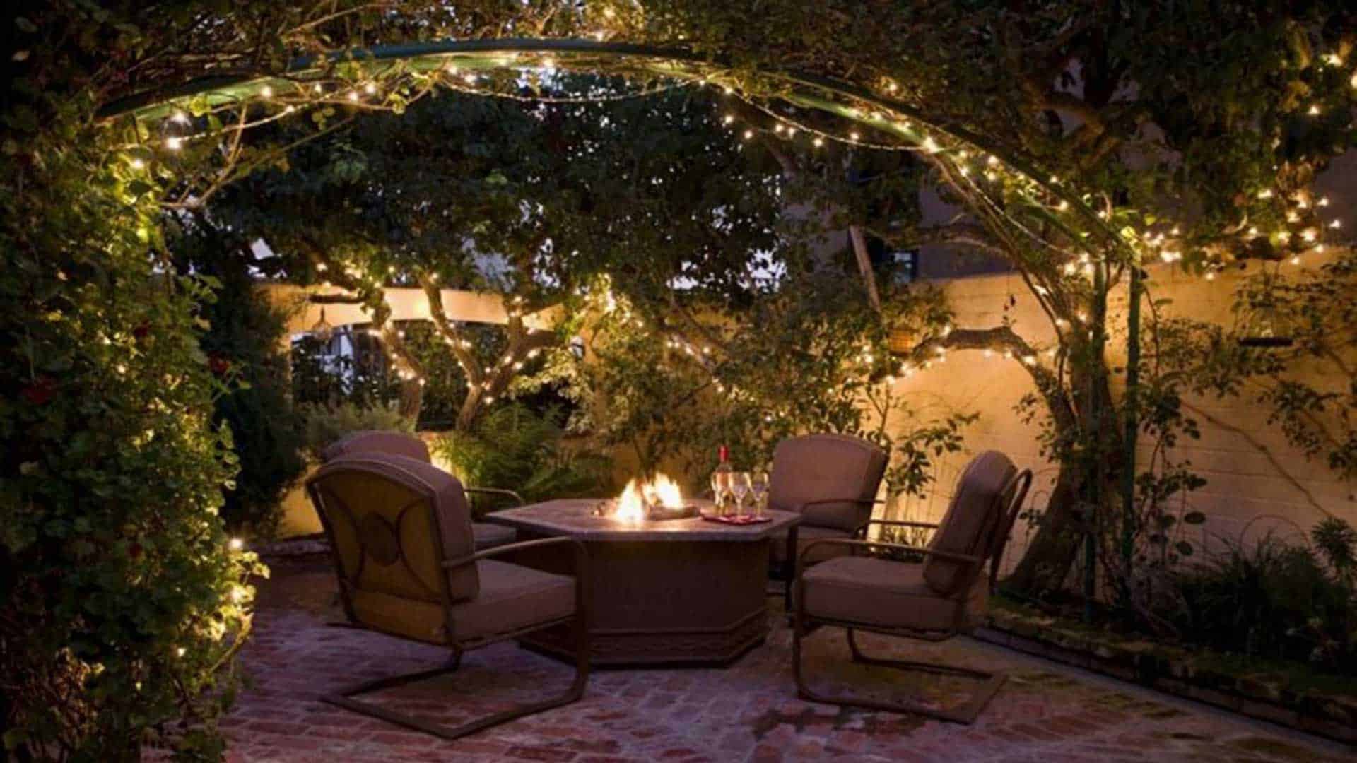 led fairy lights forming arbor over outdoor table and chairs