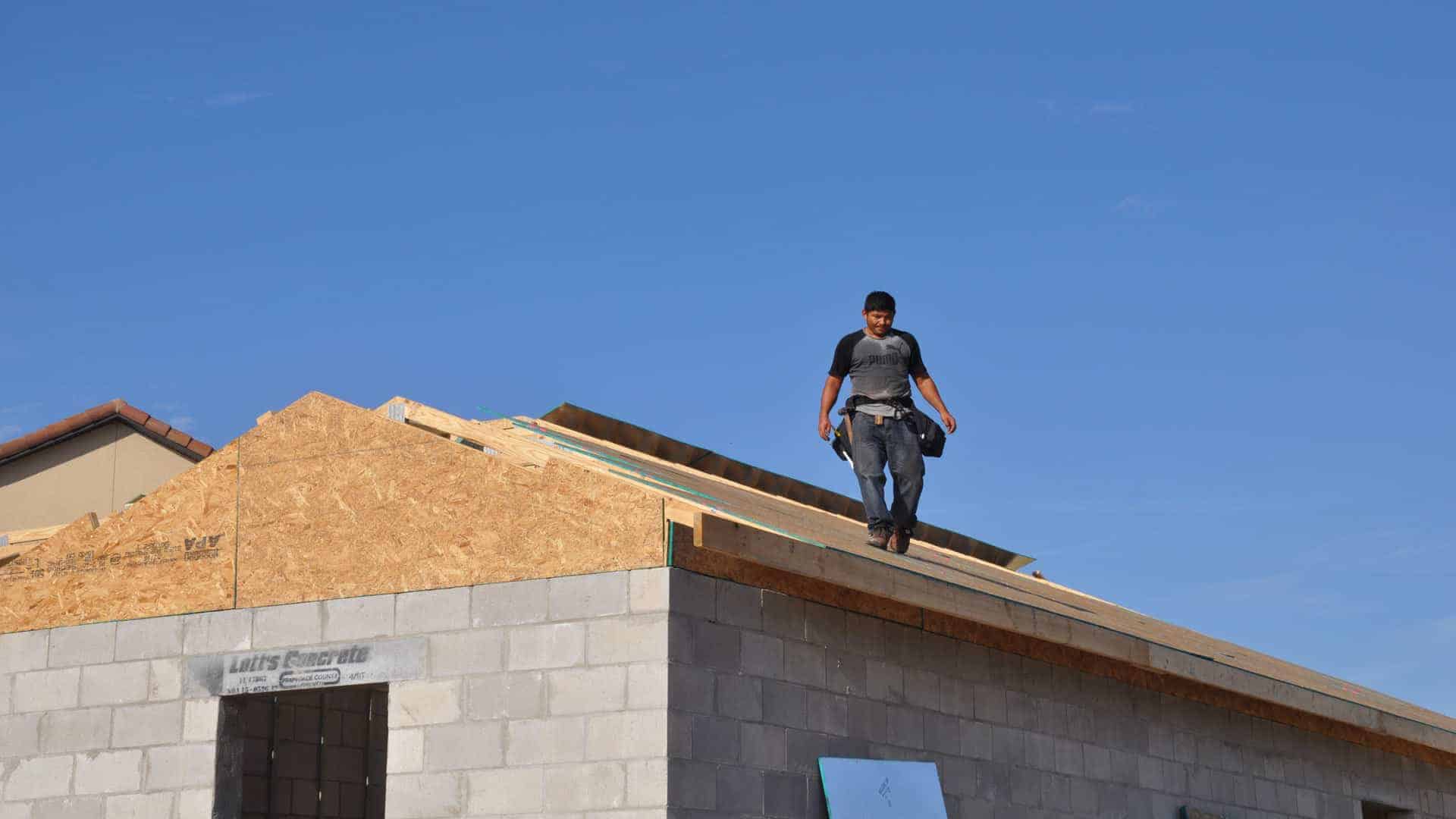 roof installer walking on roof decking panels already installed