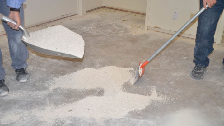 Men sweeping up popcorn ceiling texture after it falls to the ground