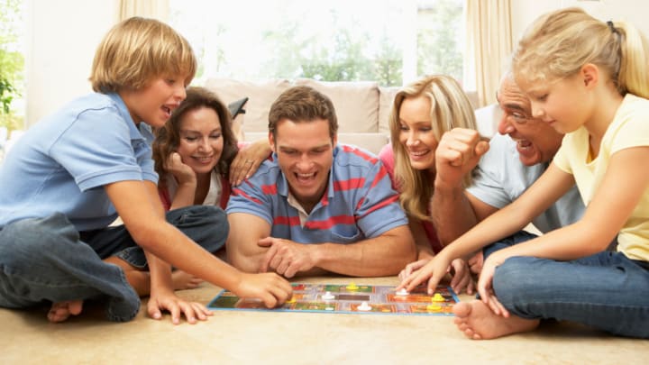 Family playing a board game, an old and returning/new holiday traditions