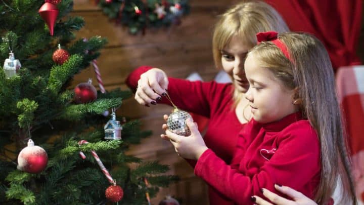 Mom decorating Christmas tree with her daughter, a very common holiday traditional 