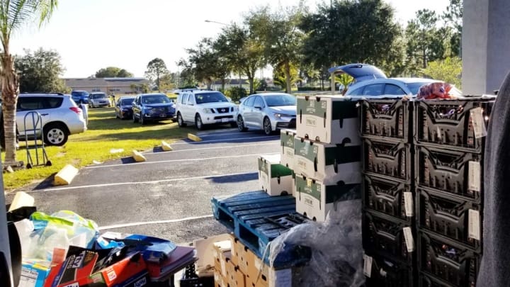 Cars lined up at a mobile food pantry, waiting for a box of food ...