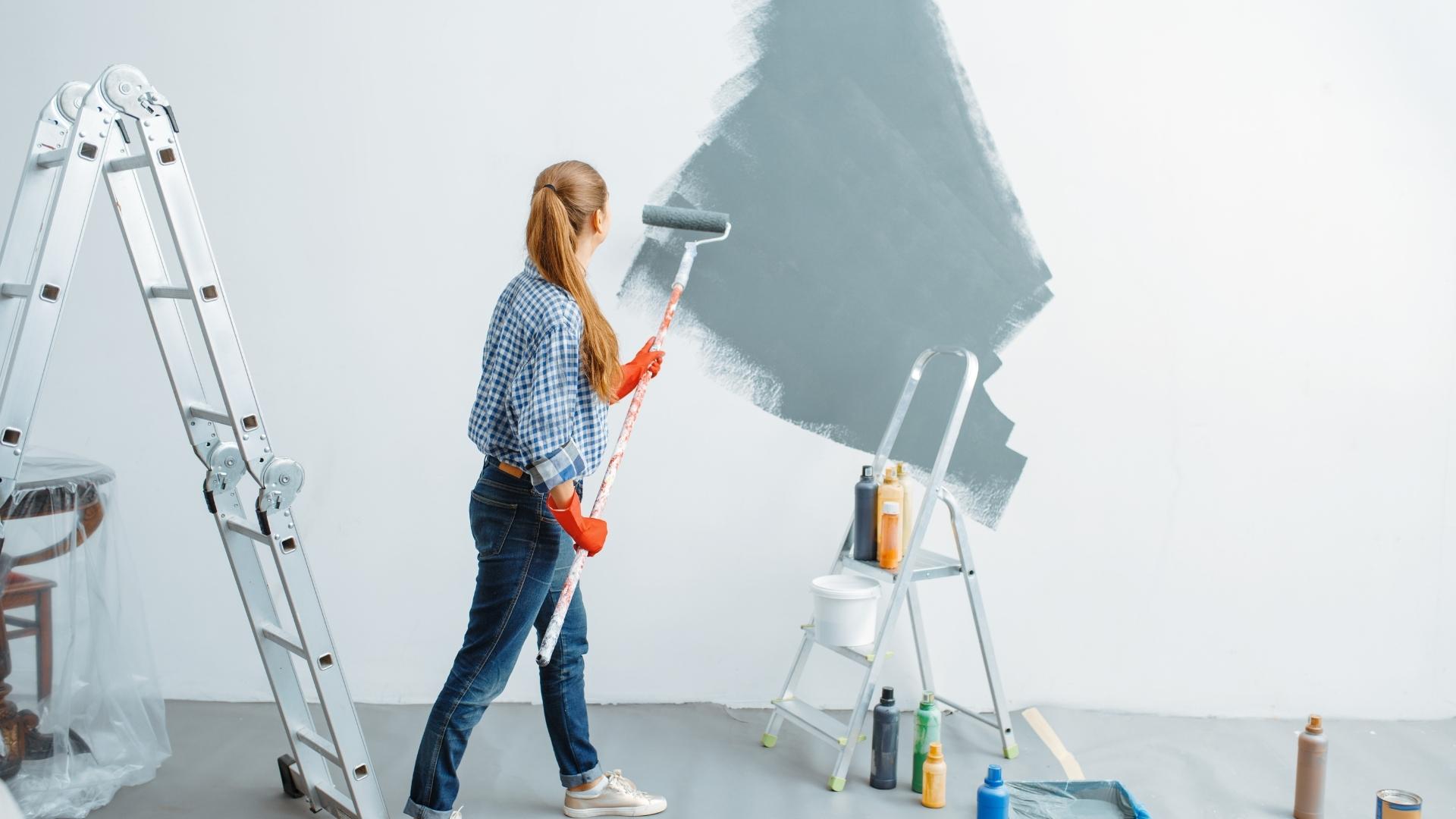 Homeowner painting a room in her house, the most common house upgrade after buying a home